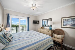 Habitación de hotel con cama, cómoda, una silla, televisor y vista al océano.