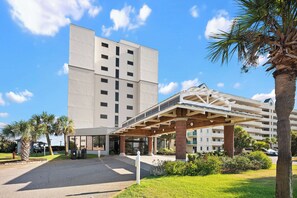 Ein mehrstöckiges Hotel mit Eingangsbereich, Palmen und blauem Himmel.