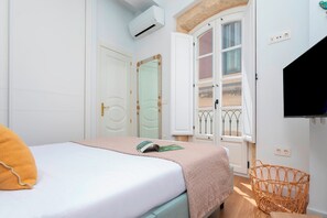 Ein Schlafzimmer mit einem Bett, einem Fenster mit Blick, einem Fernseher und einem Korbsessel.