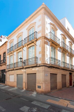 Um edifício com vários andares, varandas, janelas amplas e entrada no andar térreo fechada.