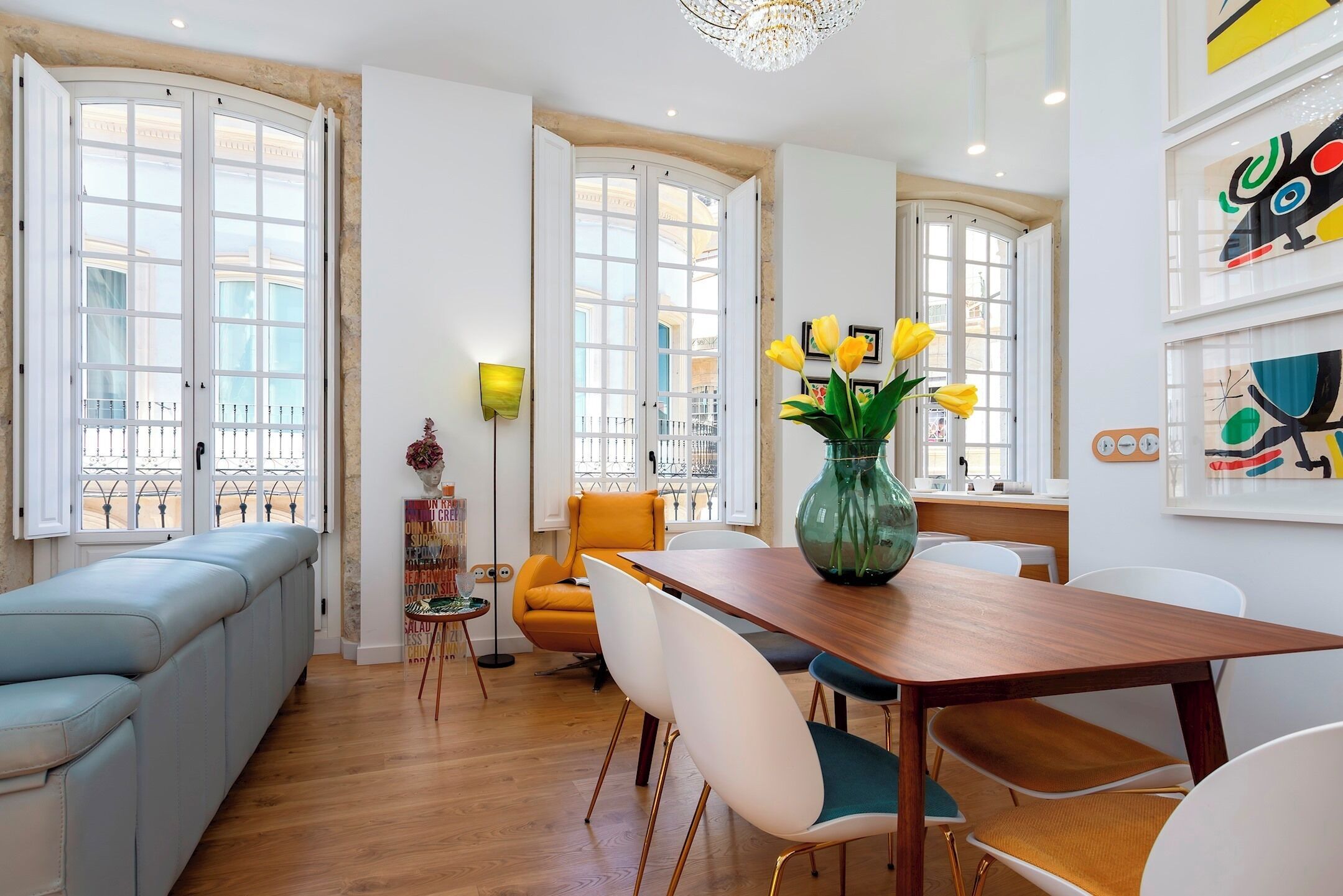 Un espacio habitable moderno con comedor, sofá y una mesa con sillas.