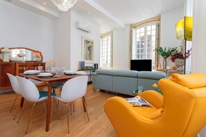 Ein modernes Wohnzimmer mit Essbereich, einer Couch und einem gelben Sessel.