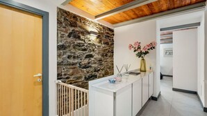 A reception area with a stone wall, a wooden door, a white reception desk, and a vase with flowers.