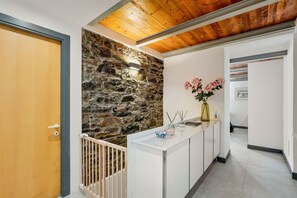 A reception area with a stone wall, a wooden door, a white reception desk, and a vase with flowers. - [Al Castello] 5Terre-Near the station+A/C (La Spezia)