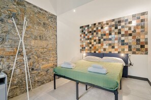 Ein Schlafzimmer mit Steinwand, einem Bett mit grüner Bettwäsche und einem Mosaik-Kopfseitenverkleidung.