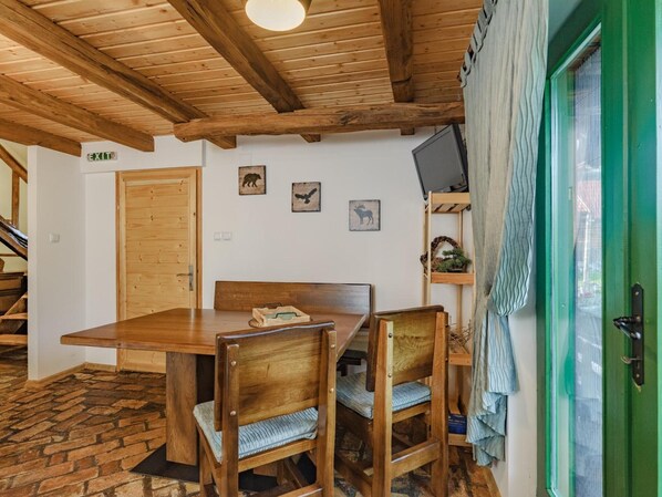 A wooden dining table with chairs, a green door, and a staircase in the background.