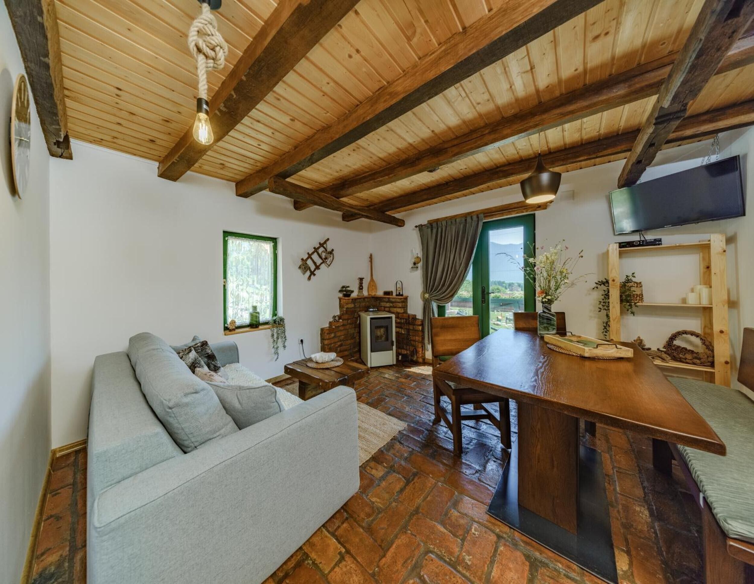 A cozy living room with a sofa, a wooden dining table, a fireplace, and a television.