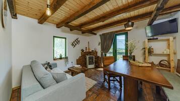 A cozy living room with a sofa, a wooden dining table, a fireplace, and a television.