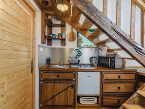 Une cuisine compacte dotée de meubles en bois, d’un évier encastré, d’un petit réfrigérateur et d’un four à micro-ondes.