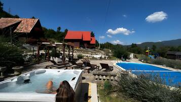 A hot tub area with a pool, outdoor seating, and a view of the surrounding landscape.