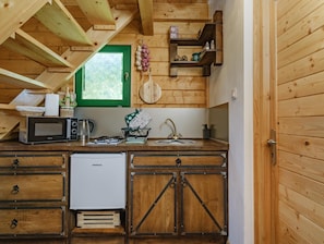 Une cuisine compacte dotée de meubles en bois, d’un four à micro-ondes, d’une bouilloire et d’un petit réfrigérateur.