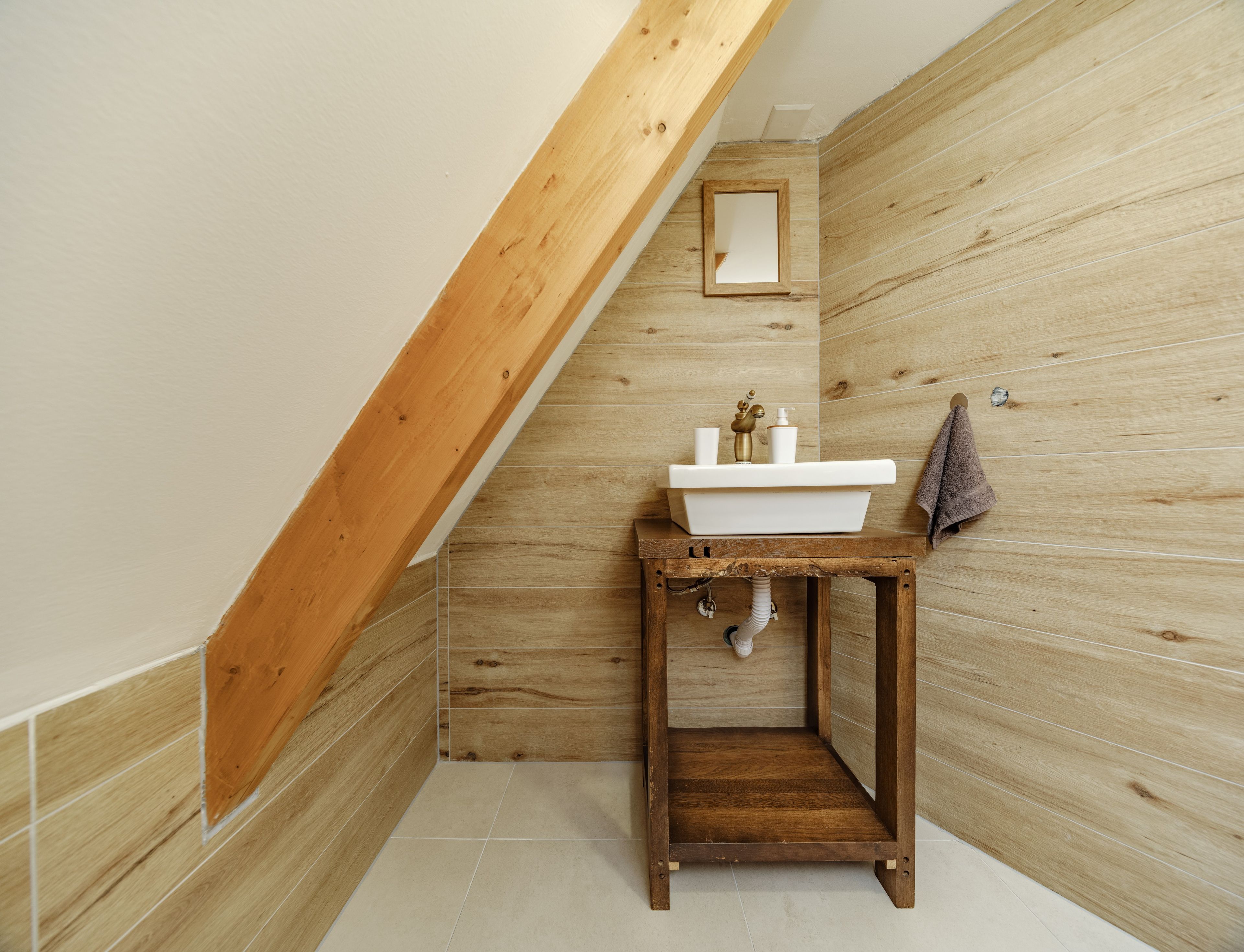 A bathroom with a wooden vanity, a white sink, and a mirror.