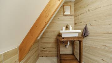 A bathroom with a wooden vanity, a white sink, and a mirror.