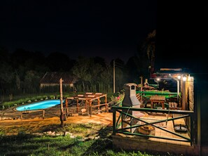 A pool area with a wooden deck, lounge chairs, and a barbecue grill.