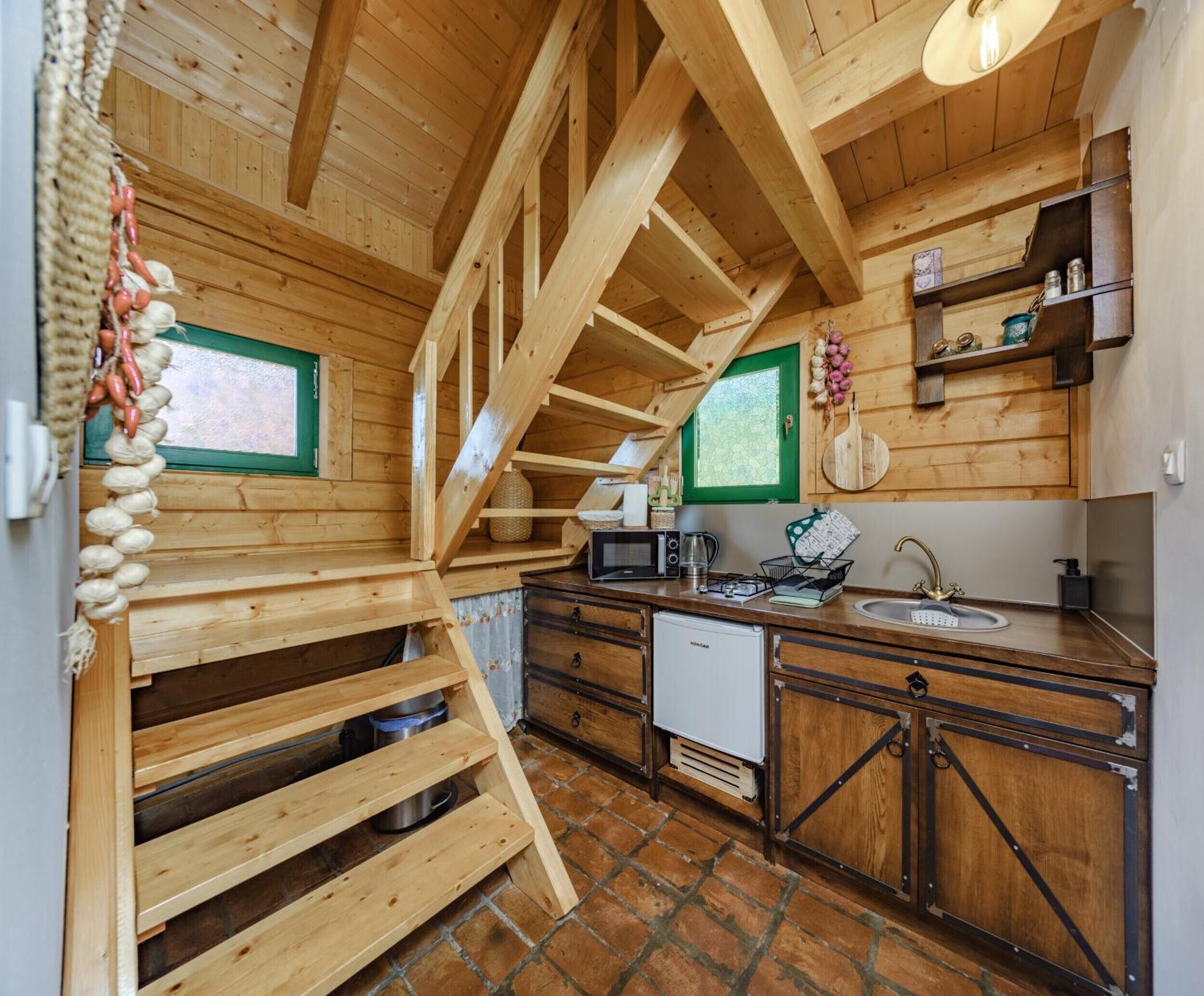 Un interno in legno con angolo cottura, comprensivo di fornello, lavello e pensili in legno.