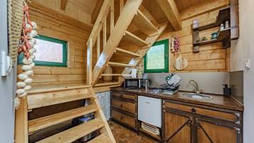 Un interno in legno con angolo cottura, comprensivo di fornello, lavello e pensili in legno.