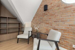 A modern loft bedroom with exposed brick walls, built-in wooden shelving, and a skylight. - Sedan Apartments  Gdansk by Noclegi Renters (Gdańsk)