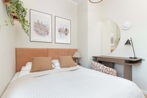 A hotel room with a bed, two framed cityscape pictures, a mirror, a desk, and a lamp. - Sedan Apartments  Gdansk by Noclegi Renters (Gdańsk)