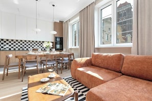 Un salon moderne comprenant un canapé, une table à manger pour quatre personnes et un coin cuisine équipé d’un four à micro-ondes et d’un four traditionnel.