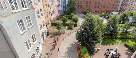 A courtyard with a cobblestone path, surrounded by multi-story buildings with various architectural styles.