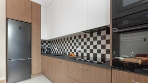 Une cuisine moderne avec un réfrigérateur en acier inoxydable, un four noir et un pare-feu à carreaux.