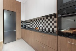 A modern kitchen with a stainless steel refrigerator, a black oven, and a checkered backsplash. - Sedan Apartments  Gdansk by Noclegi Renters (Gdańsk)