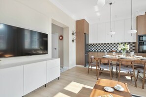 Eine moderne Küche mit einem großen Flachbildfernseher, Holzschränken und einer karierten Spritzschutzwand.