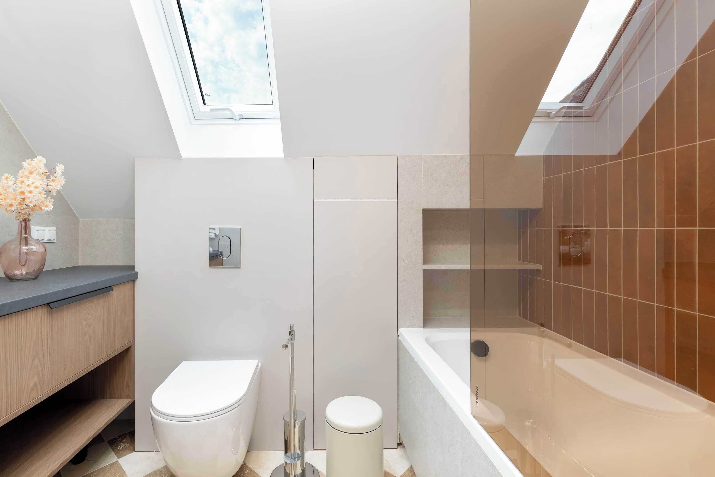 Ein modernes Badezimmer mit einem Oberlicht, einer Toilette, einem Bidet, einer Dusche und einer Badewanne.