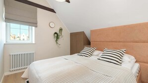 Une chambre à coucher avec un lit, une fenêtre, un radiateur, une horloge et une plante.