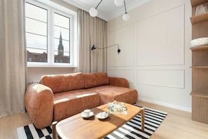 A modern living room with a brown sofa, a wooden coffee table, and a striped rug. - Sedan Apartments  Gdansk by Noclegi Renters (Gdańsk)