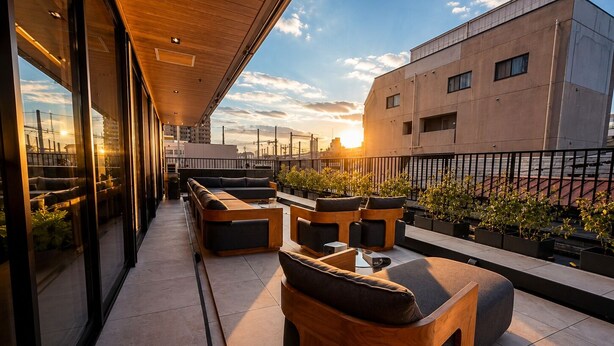 A rooftop terrace with outdoor seating, potted plants, and a view of the sunset. - Flam Hotel Luxury Penthouse Osaka | Sauna & Rooftop Terrace Near USJ (大阪市)