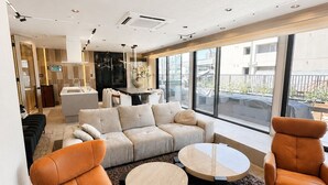 A modern living room with a sofa set, two armchairs, a coffee table, and a large window offering a view of the outside. - Flam Hotel Luxury Penthouse Osaka | Sauna & Rooftop Terrace Near USJ (大阪市)