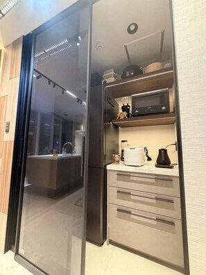 A modern kitchen with a built-in microwave, a coffee maker, and a blender on the countertop. - Flam Hotel Luxury Penthouse Osaka | Sauna & Rooftop Terrace Near USJ (大阪市)
