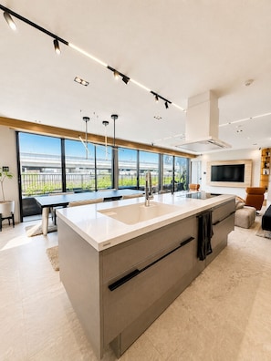 A modern kitchen with a large island, built-in appliances, and a view of a bridge.