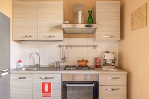 Une cuisine avec des meubles de rangement en bois, un évier en acier inoxydable, une cuisinière et une machine à café.