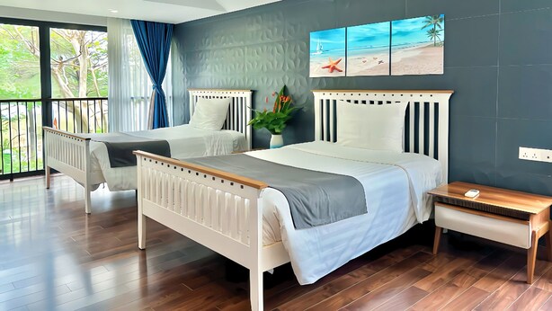 A modern bedroom with two beds, a balcony, and a view of greenery. - Maribel Villa Phu Quoc 4BR - Private Pool (Phú Quốc)