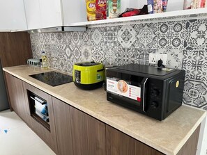 A kitchen with a microwave, a green appliance, and a tiled backsplash. - Maribel Villa Phu Quoc 4BR - Private Pool (Phú Quốc)