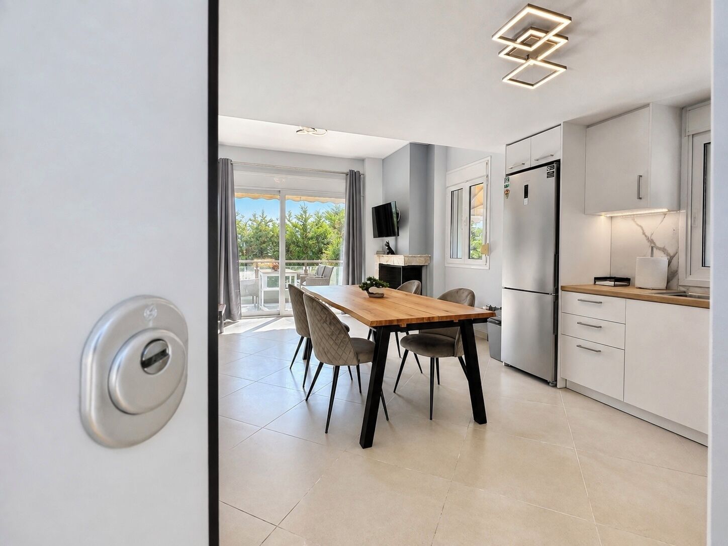 Une cuisine moderne avec un coin repas, un téléviseur à écran plat et une vue sur l’extérieur.