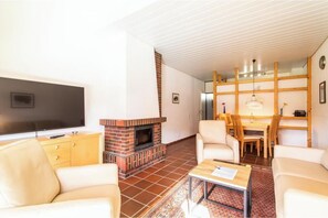 Ein Wohnzimmer mit Kamin, Fernseher und Essbereich mit Stühlen und Tisch.