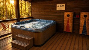 Een hottub in een houten chalet met een houten terras en een bordje dat een speelkamer aangeeft.