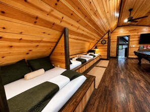 A cozy attic bedroom with wooden walls, a sloped ceiling, and a pool table. - Secluded Cabin Perfect for Couples & Families with Hot Tub & Stone Fireplace in Broken Bow, Oklahoma (Broken Bow)