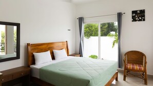 A bedroom with a bed, a nightstand, a chair, a ceiling fan, and a window with curtains. - Ocean Blue villa 2bhk (Cheyyur (Taluk) / Vadapattinam)