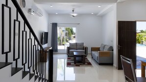 A modern living room with a staircase, a sofa, a coffee table, and a television. - Ocean Blue villa 2bhk (Cheyyur (Taluk) / Vadapattinam)