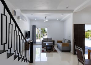 Una sala de estar moderna con una escalera, un sofá, una mesa de centro y un televisor.