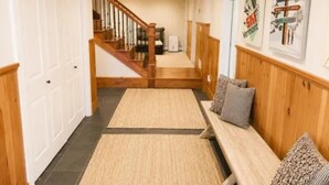 A hallway with a wooden bench, a staircase, and a door. - Luxury 4-bedroom Ski house in Stratton with Shuttle or Walk to Slope Options (Stratton)