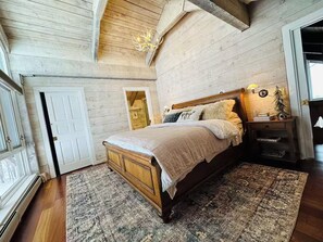 Ein Schlafzimmer mit einem Holzbett, einem Nachttisch, einer Lampe und einem Fenster.