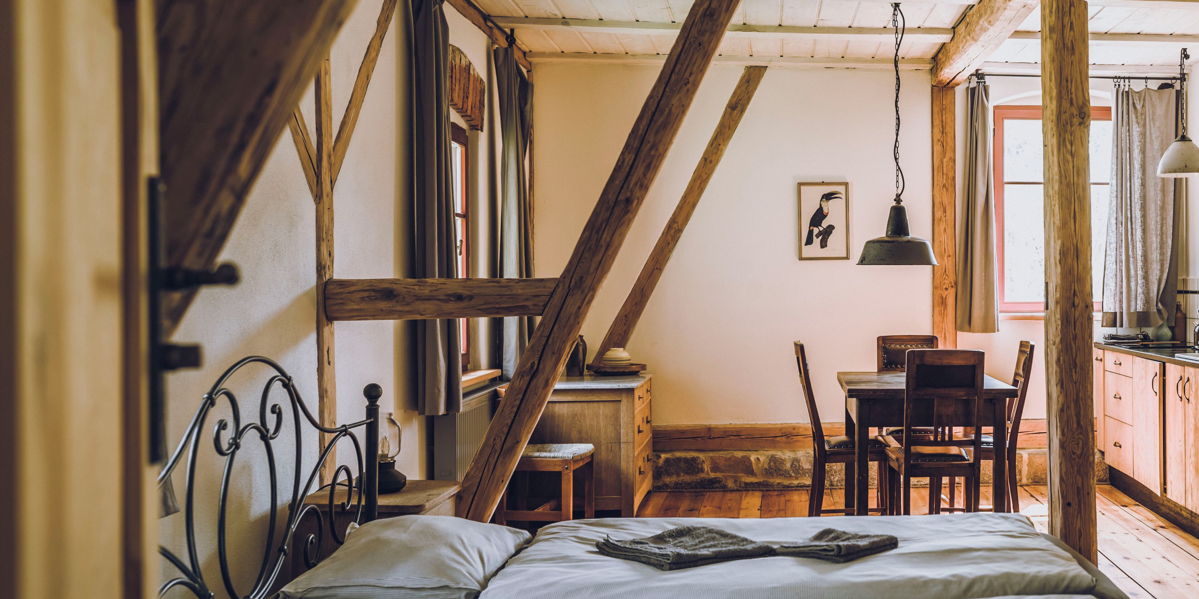 Ein rustikales Schlafzimmer mit freiliegenden Holzbalken, einem Bett, einem Schreibtisch und einem Stuhl.