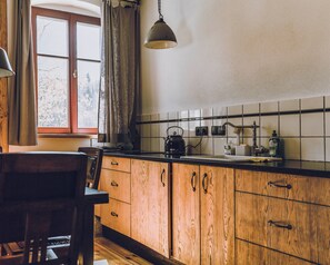 A kitchen with wooden cabinets, a black countertop, a kettle, and a window with curtains. - Dom Sokolik – A Natural Paradise with Mountain Views, Family- and Dog-Friendly (Janowice Wielkie)
