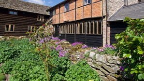 Ein traditionelles Steinhaus mit Satteldach und einem daran angebauten Holzbau.