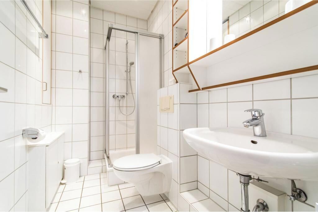 Un baño moderno con inodoro, lavamanos y ducha.